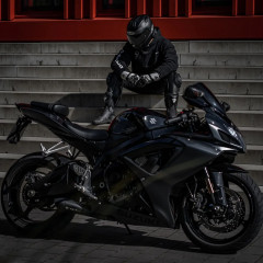 Ein Motorrad vor einer Treppe auf der ein in schwarz gekleideter Motorradfahrer sitzt