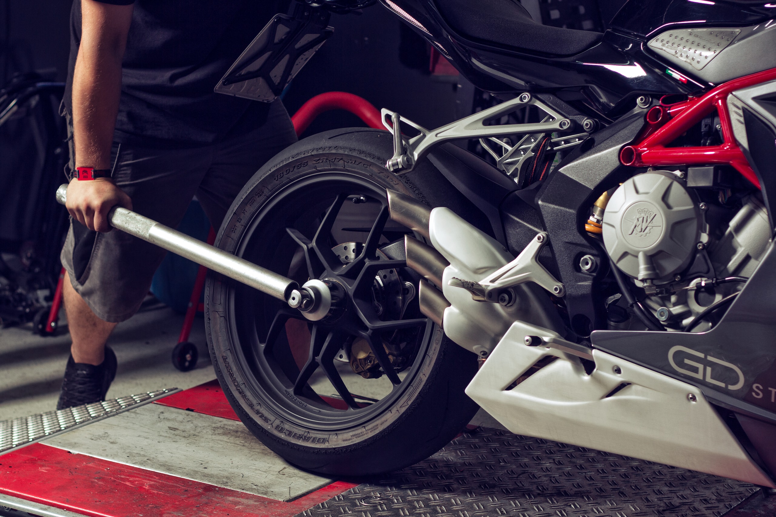 Ein Mechaniker beim festziehen des Rads eines weißen Motorrads